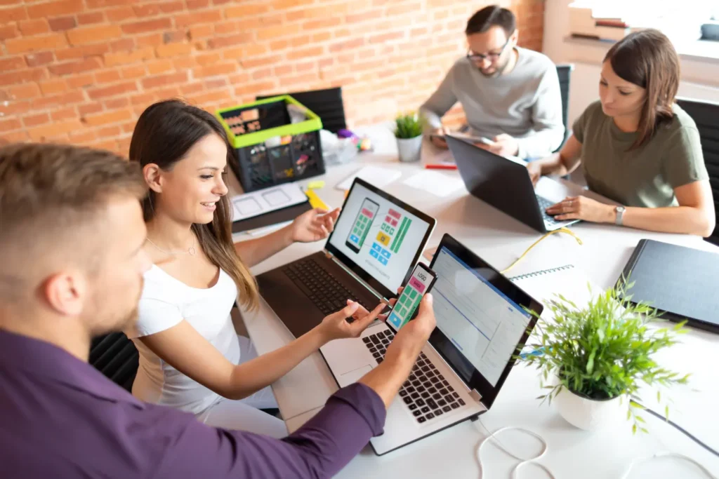a group of business people looking over a mobile web design concept - Digitech